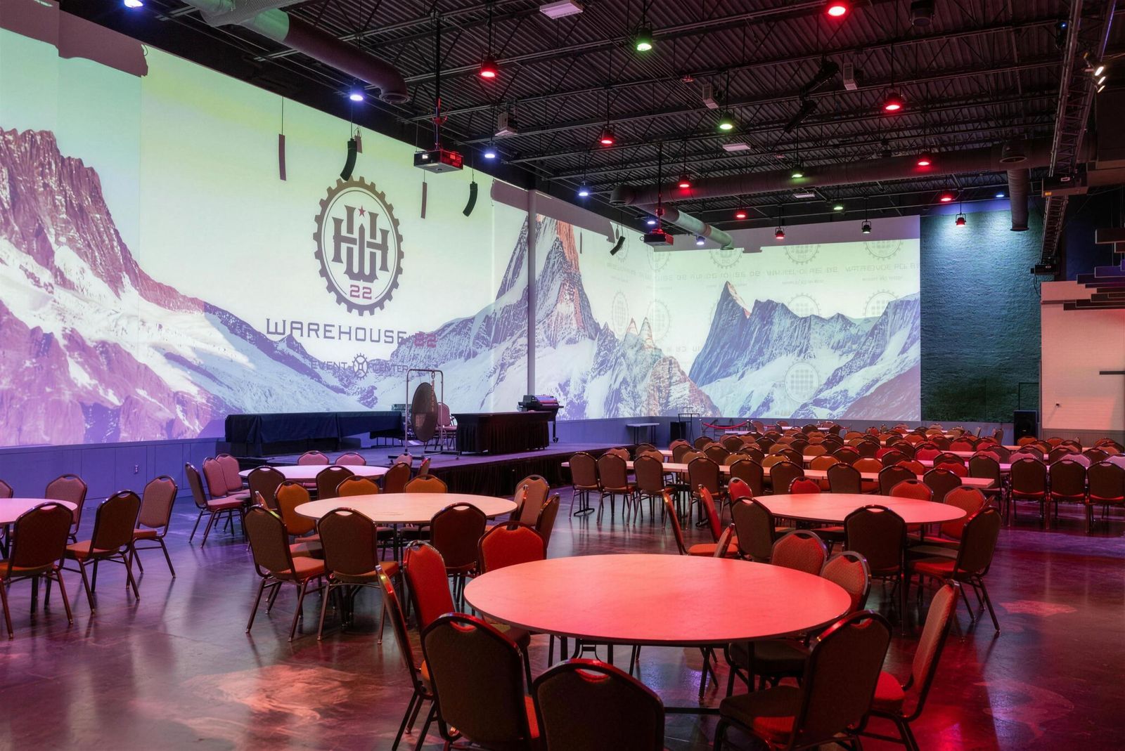 Warehouse 22 main hall set with round tables under the projection wall